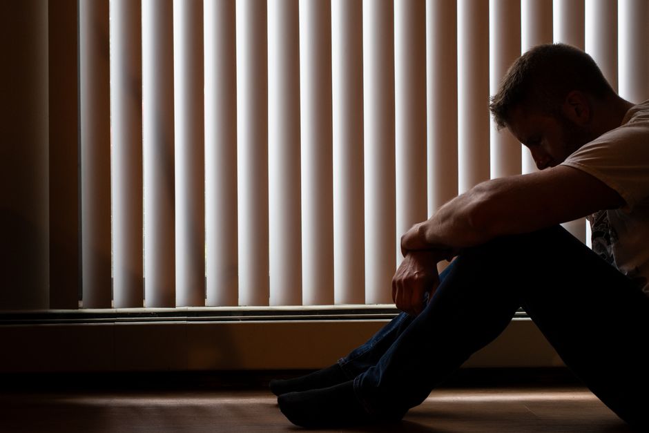 Mann blickt deprimiert aus Fenster