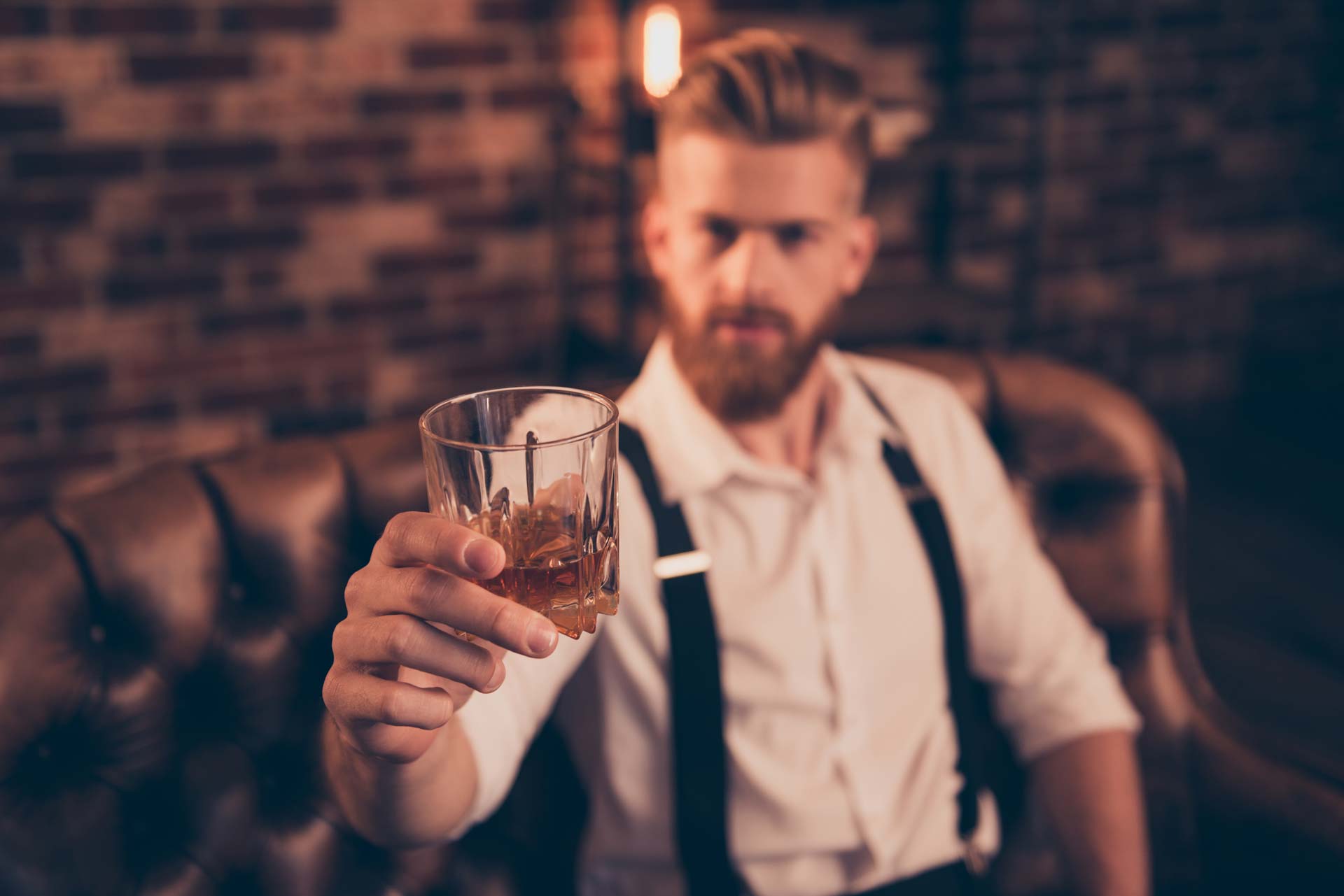 gepflegter Mann hält ein Whiskyglas