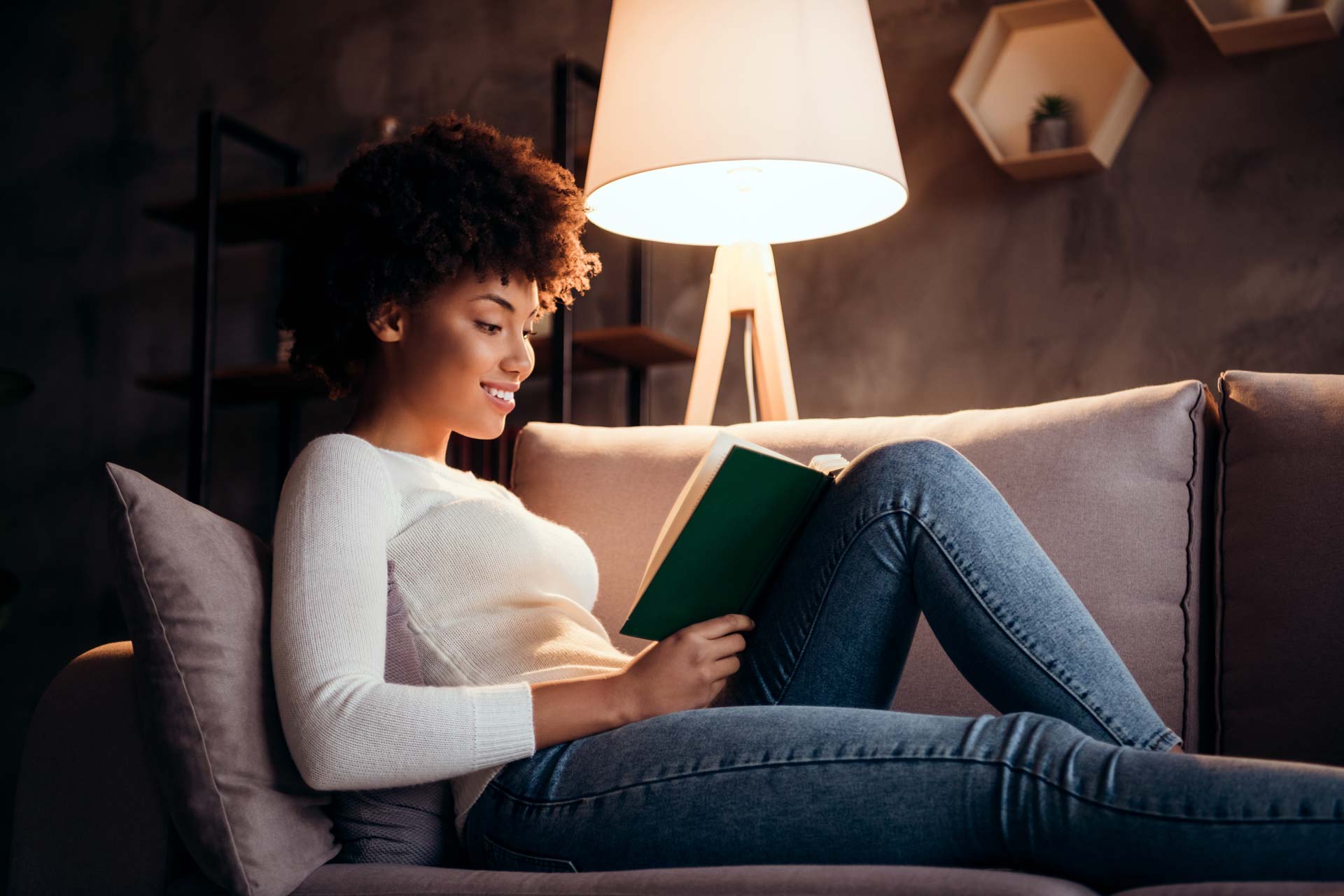 Frau sitz auf Sofa und liest ein Buch im Licht einer Standleuchte - Stehlampen Vergleich
